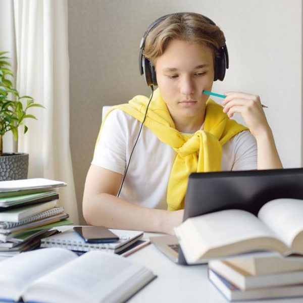 Teenager boy study at home. Online education and distance learning for children. School boy doing his physics homework using gadgets. Lectures and lessons on the internet for high school students